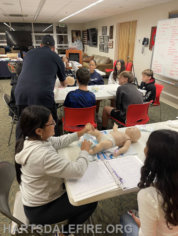 A group is training with baby mannequins, learning skills in a classroom setting.