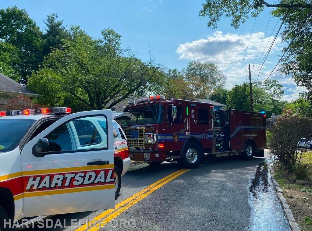 A fire truck and command vehicle on a residential street with emergency lights on.