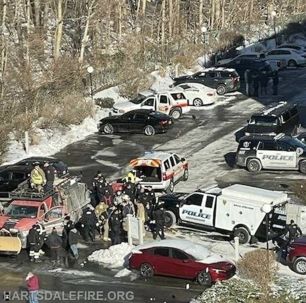 Emergency responders and police are gathered in a snowy area with multiple vehicles, likely responding to an incident.