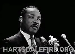 A person is speaking at a microphone. The text "HARTSDALEFIRE.ORG" is visible at the bottom.