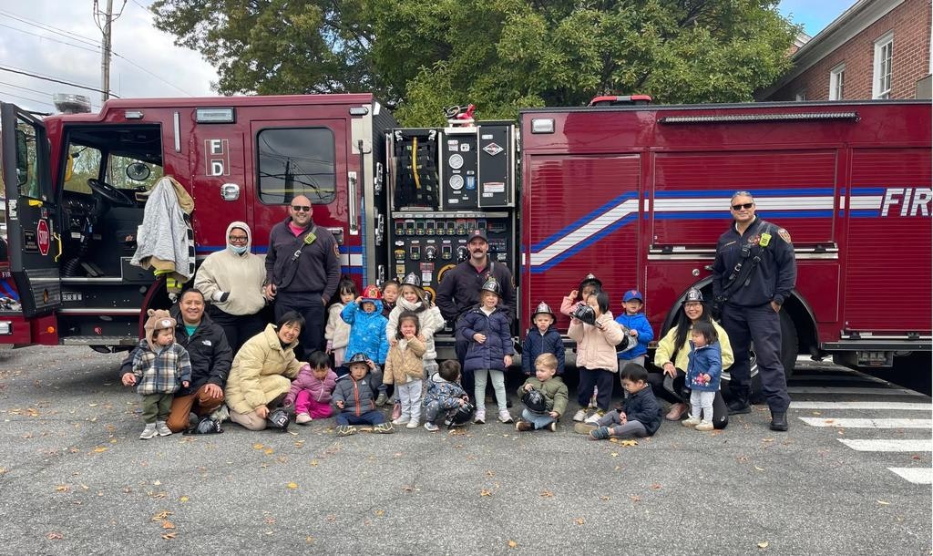 A group photo featuring firefighters and children in front of a fire truck, enjoying a community event.