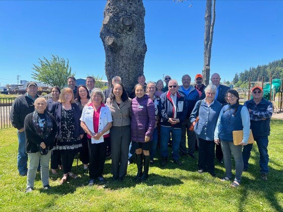 A group of people posing outdoors with a tree in the background.