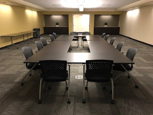 A conference room with tables, chairs, and beige walls.