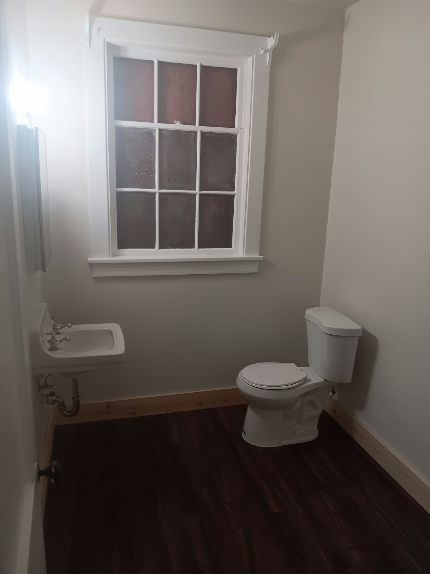 A bathroom with a wall-mounted toilet, a window, a sink, and a bathtub.