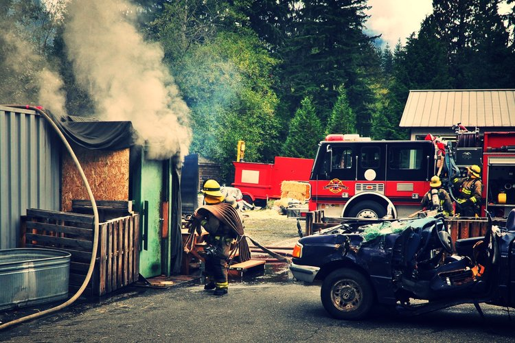 Photo of firefighter working, a firetruck, smoke, a damaged car