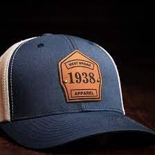 A blue and white baseball cap with a vintage style patch that reads "West Squad 1938 Apparel."