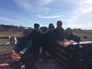 Group of people with crates of produce outdoors.