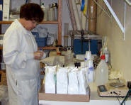 A person in a lab coat working with scientific equipment and samples.