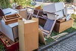 Discarded furniture and wooden pieces piled on the ground near a street.
