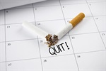 Broken cigarette on a calendar with "QUIT!" written underneath.