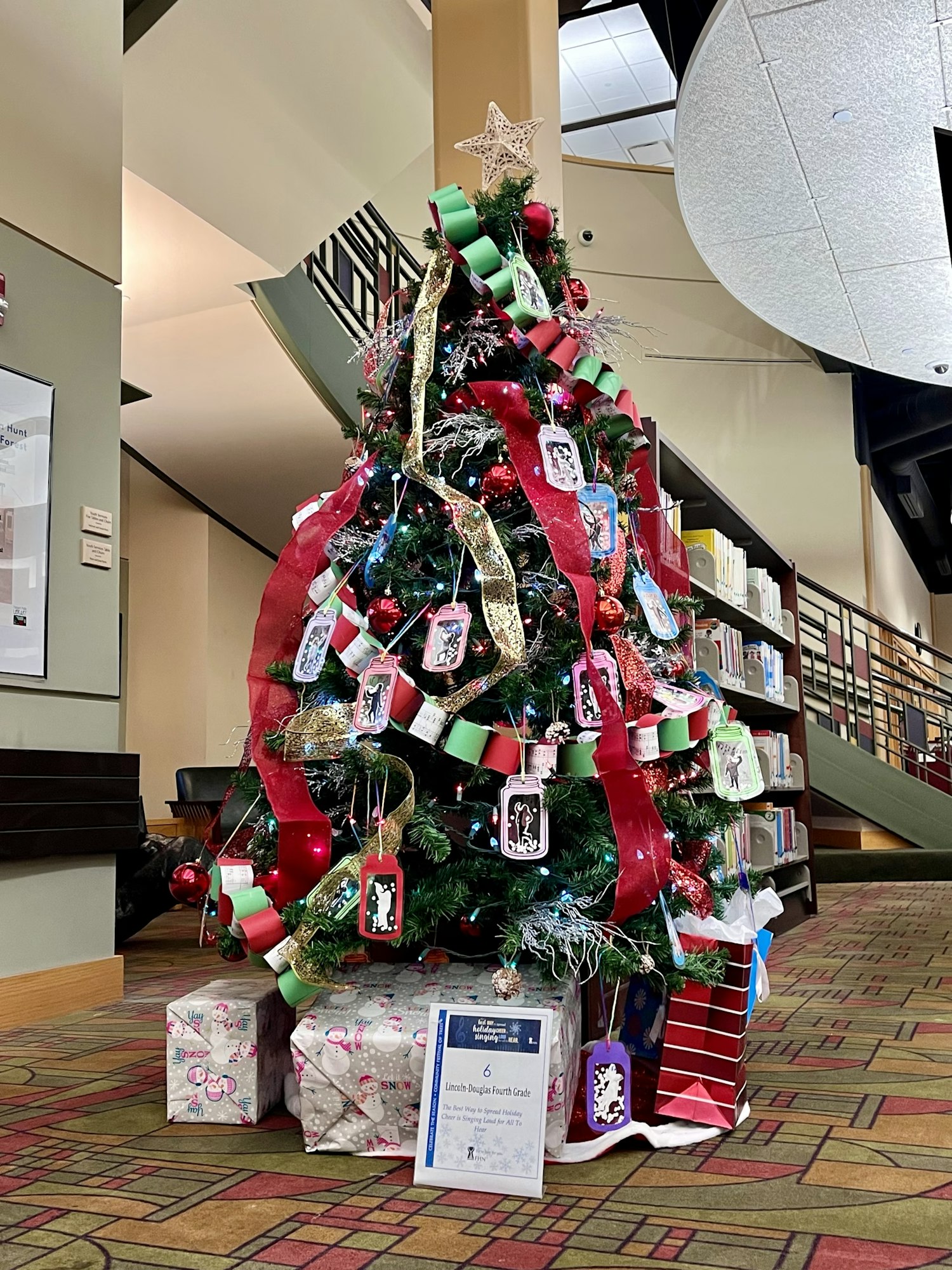 A decorated Christmas tree with red and green garlands, ornaments, and wrapped gifts underneath.