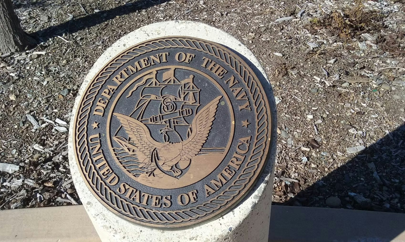 The image depicts a seal for the Department of the Navy, featuring an eagle, ship, and the text "United States of America."