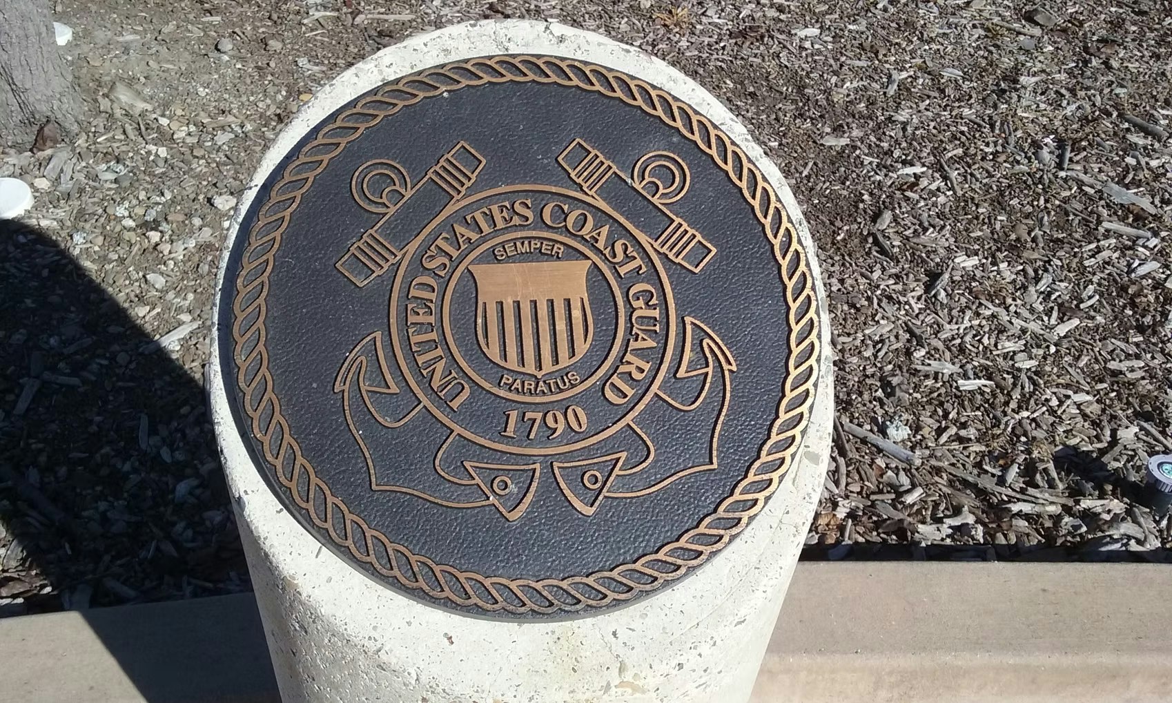 The image features a bronze seal of the United States Coast Guard, displaying its emblem, founding date (1790), and motto "Semper Paratus."