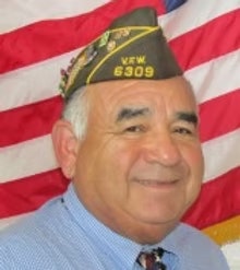 The image features a smiling man wearing a military cap and a blue shirt, with an American flag in the background.