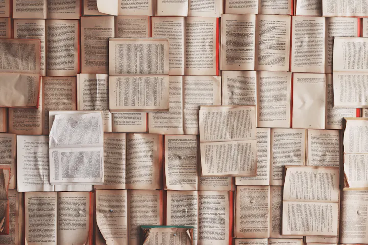 An arrangement of open books with text, forming a textured, overlapping pattern.
