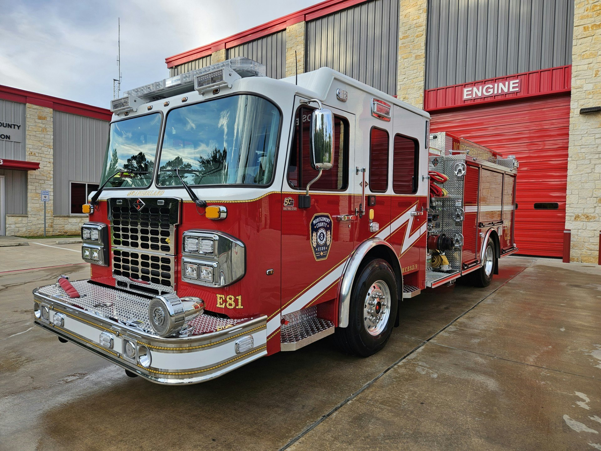 A red fire truck parked outside a fire station with a red garage door.