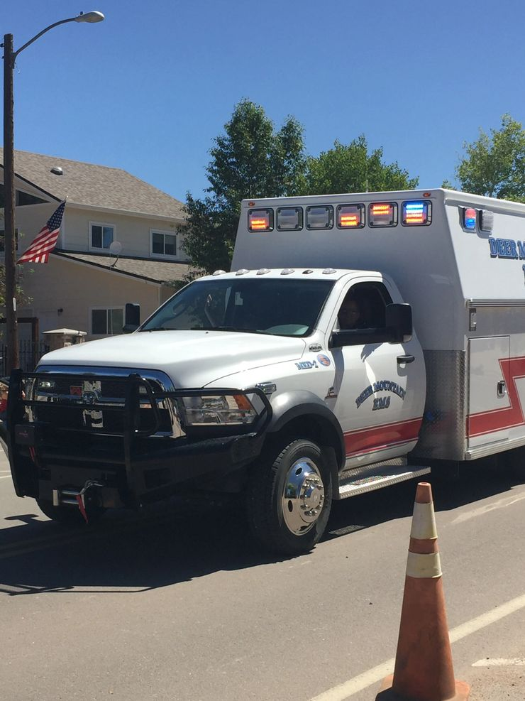 An ambulance with lights, a flag, and an orange traffic cone in front.