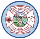 A circular emblem with a deer, firefighting tools, and text "Deer Mountain Fire Protection District, Est. 1954."