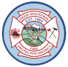 A circular emblem with a deer, firefighting tools, and text "Deer Mountain Fire Protection District, Est. 1954."