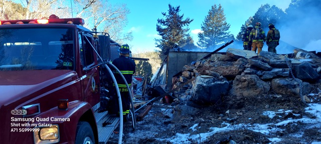 Firefighters at a smoky scene with a fire truck and rubble.