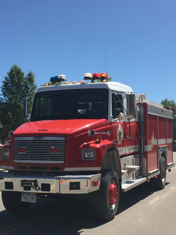 Red fire truck with emergency lights and a firefighter visible inside.