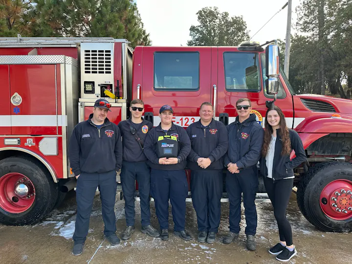 Group of firefighters posing in front of a red fire truck.