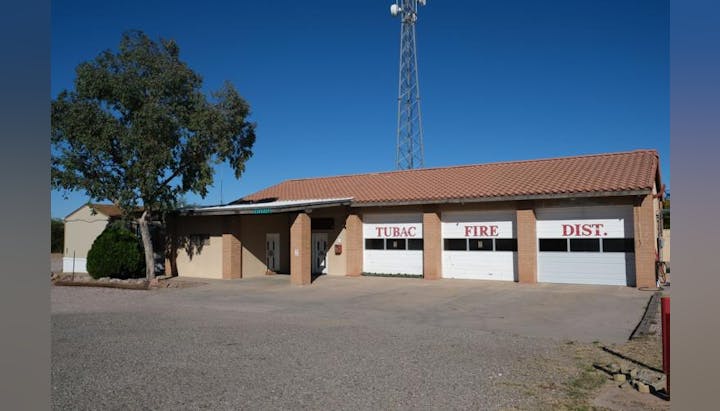 A fire station building with "TUBAC FIRE DIST." sign and garage doors.