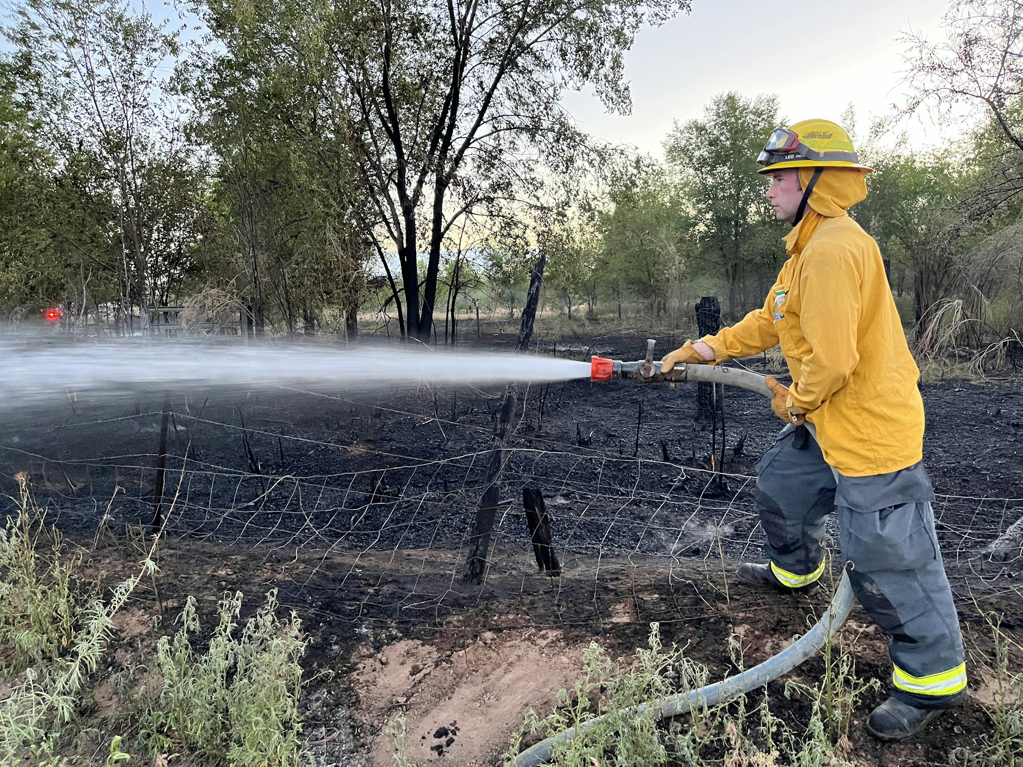 May contain: helmet, clothing, glove, extinguishing fire, fire, and person
