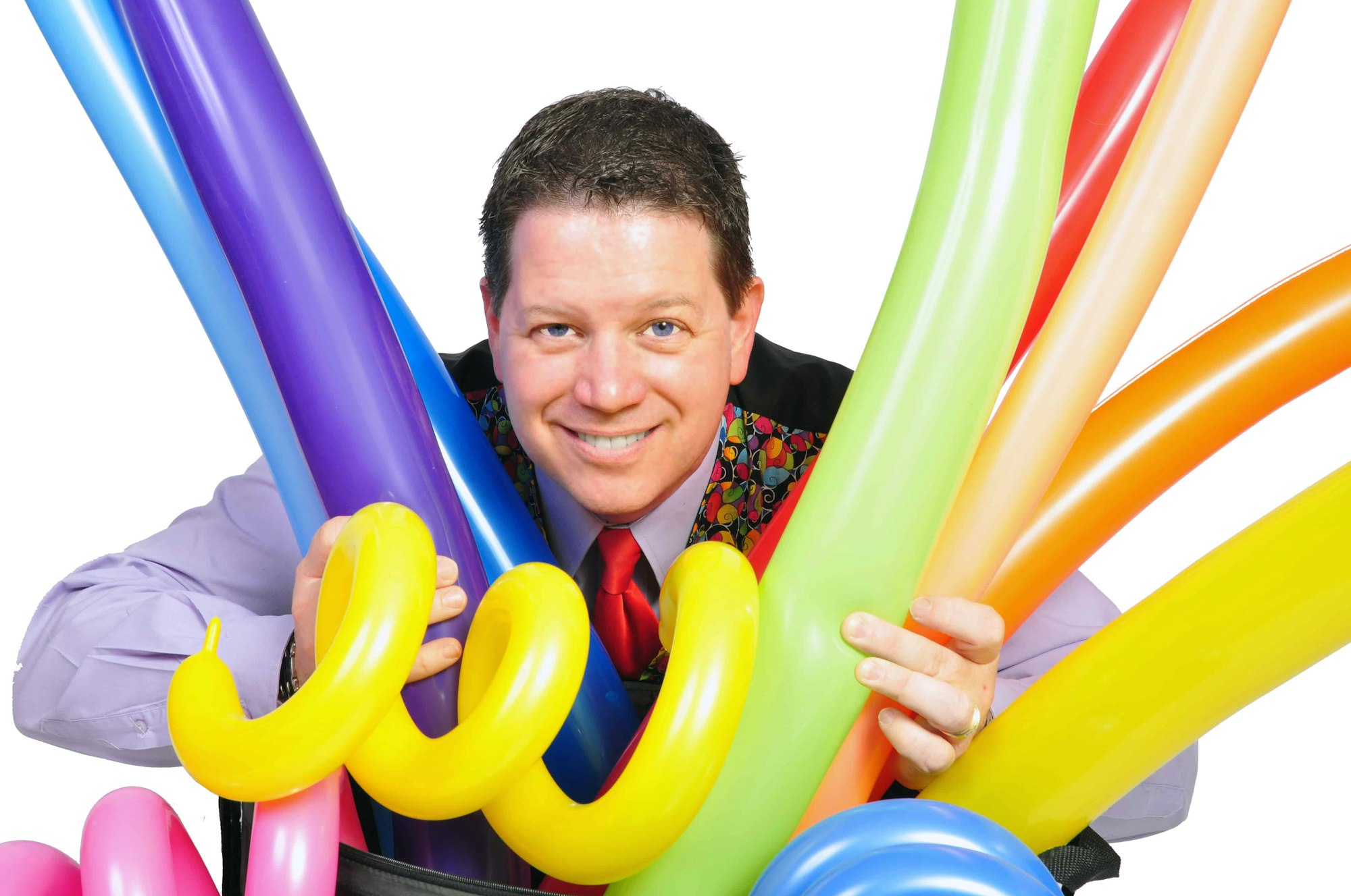 A man smiling, surrounded by colorful inflated balloon sculptures.