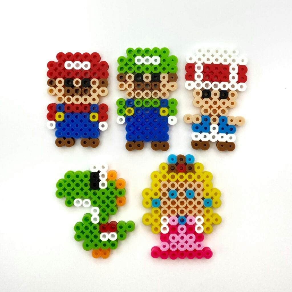 The image features colorful pixel art figures of Mario, Luigi, Toad, Yoshi, and Princess Peach made from fuse beads.