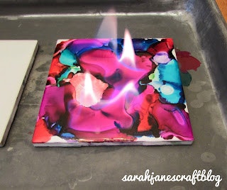 Colorful, melted crayon art with a flame above it, on a foil-lined tray.