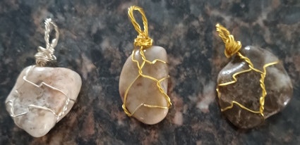 Three wire-wrapped crystal pendants on a dark surface.