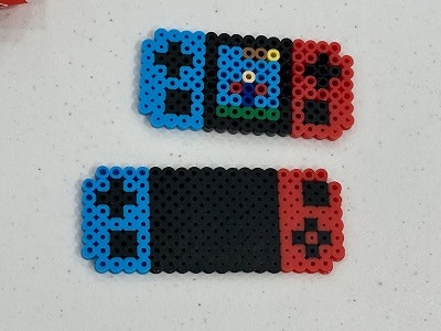 Two bead art pieces resembling a gaming console and its controllers.