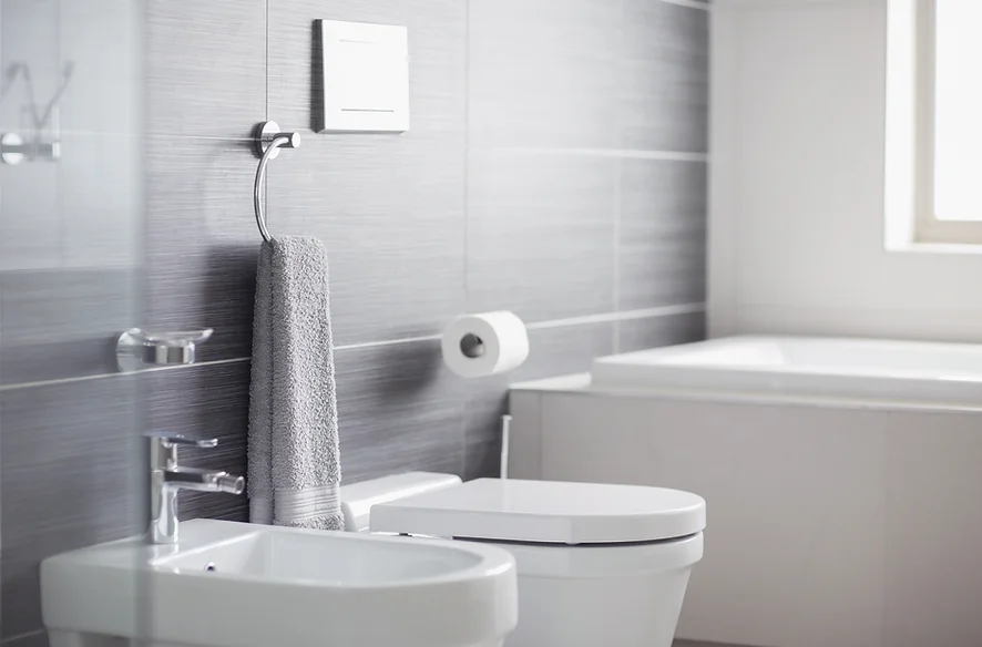 A modern bathroom with a sink, toilet, towel, and a bathtub.