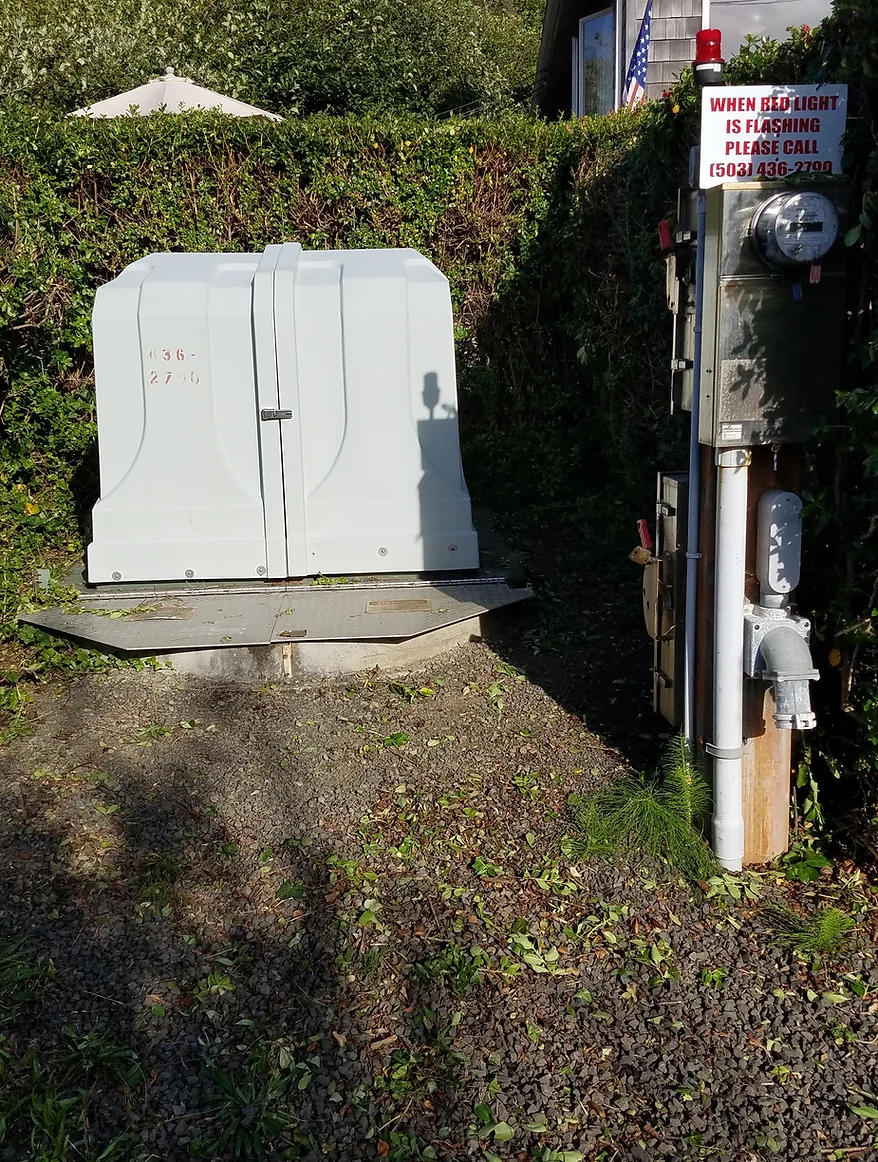 A utility box next to a sign and electric meter, with vegetation in the background.
