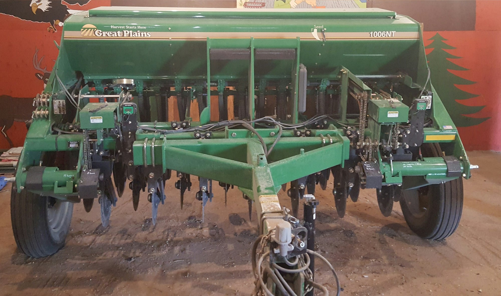 A green Great Plains drill seeder used for planting crops, stored indoors.