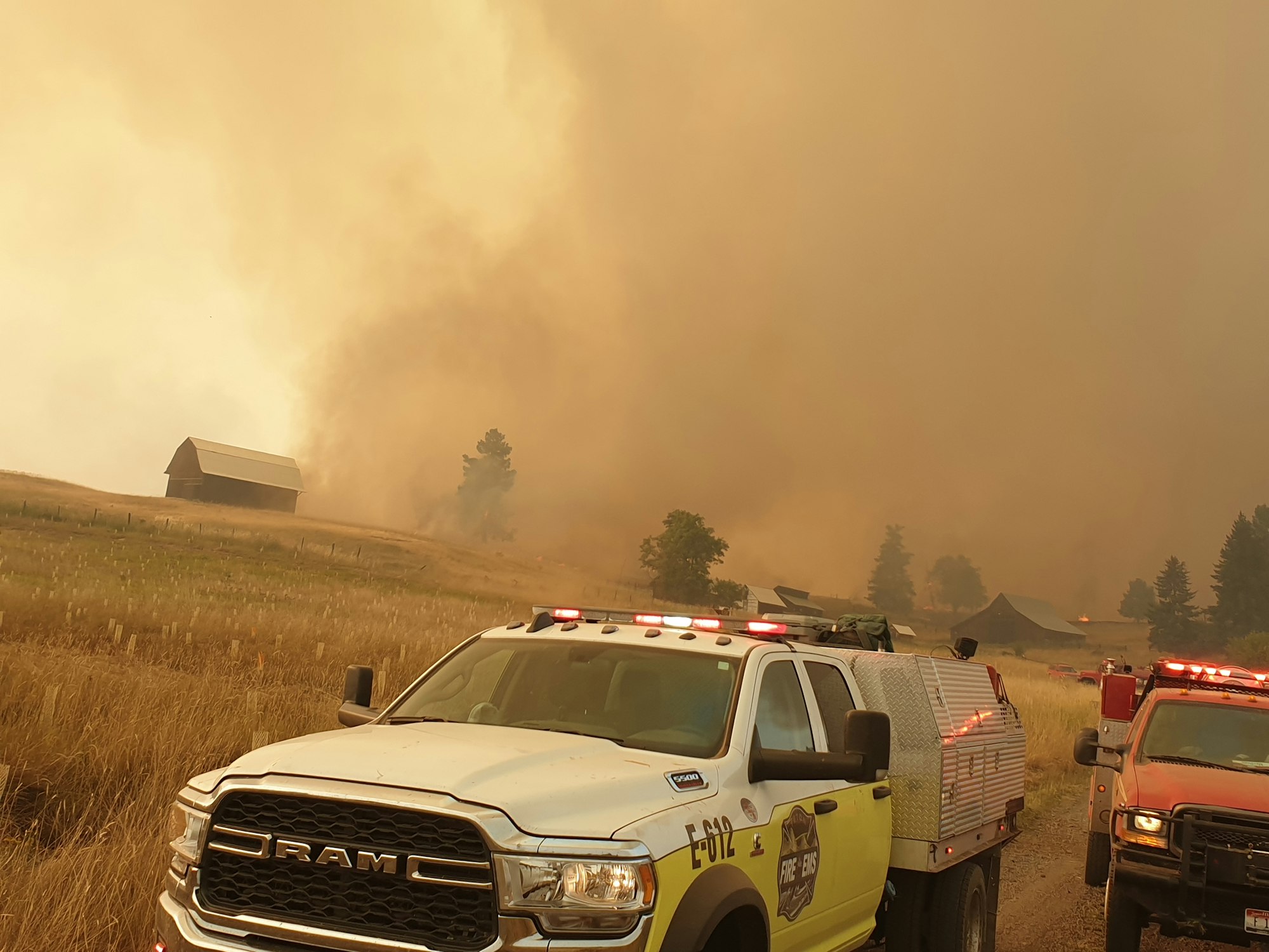 Wildfire with emergency vehicles and heavy smoke.