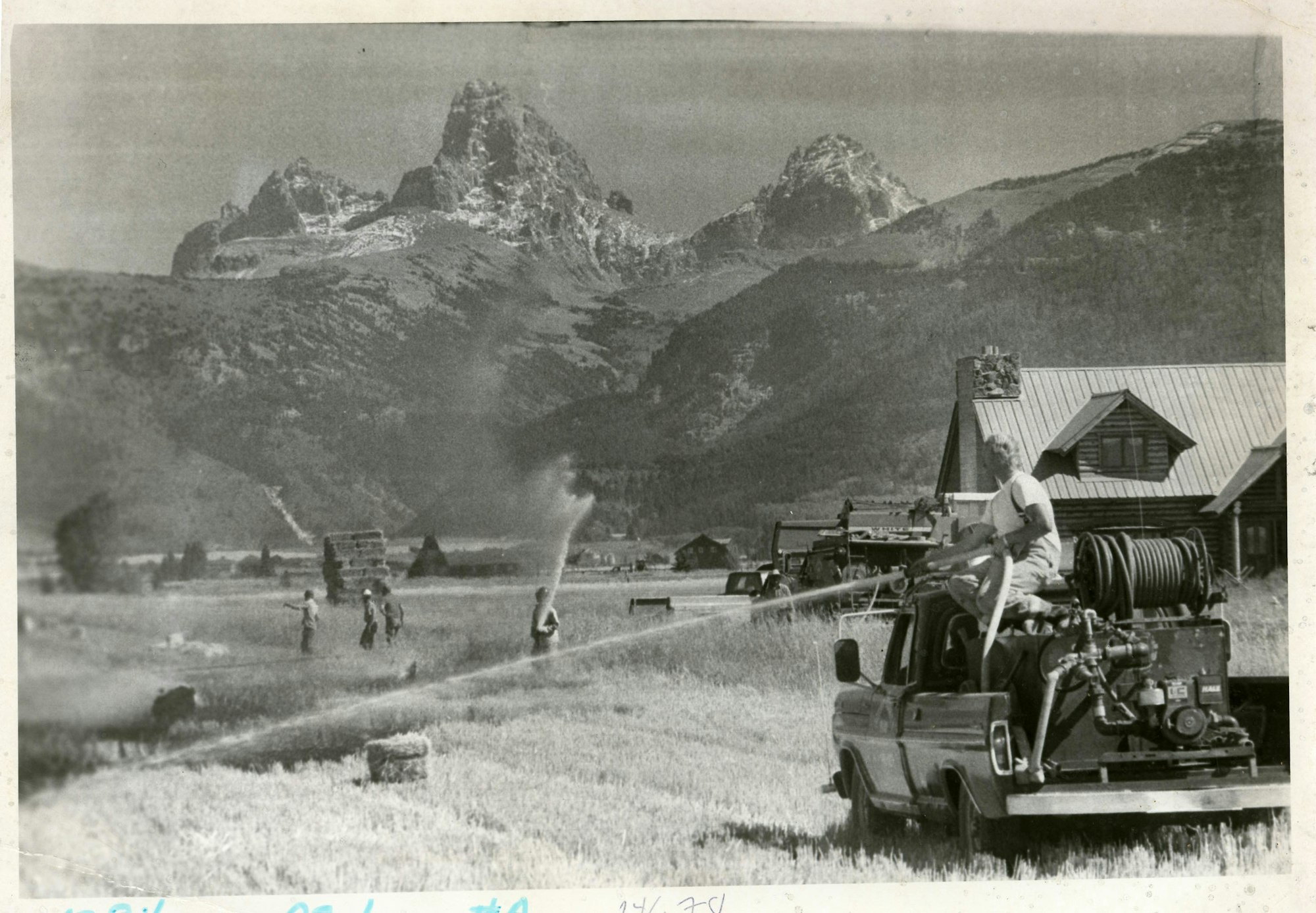 Rural firefighting scene with people, truck, mountain backdrop.