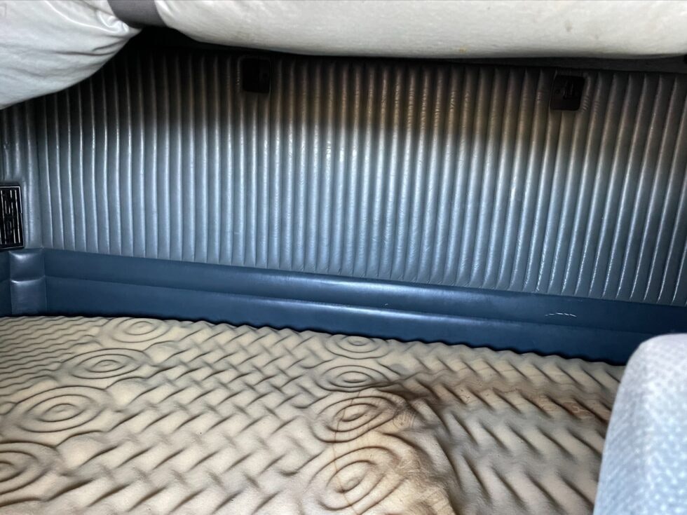 Interior view of a truck's sleep cabin with bed and textured wall.
