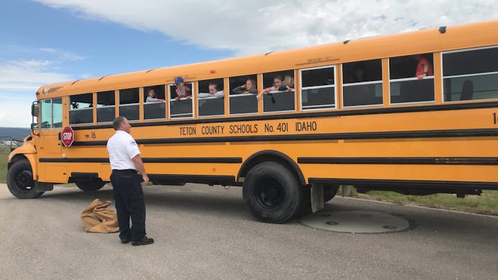 A school bus with children at the windows and an adult outside, likely during a safety drill or stop.