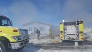 Firefighters and a fire truck at a smoky scene, possibly addressing a fire incident.