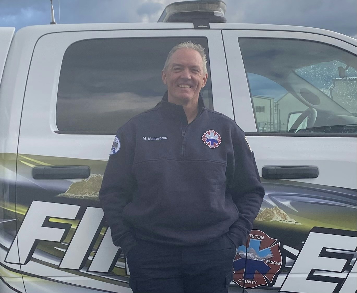 A person standing in front of a white emergency vehicle with "FIRE" partially visible on the side.