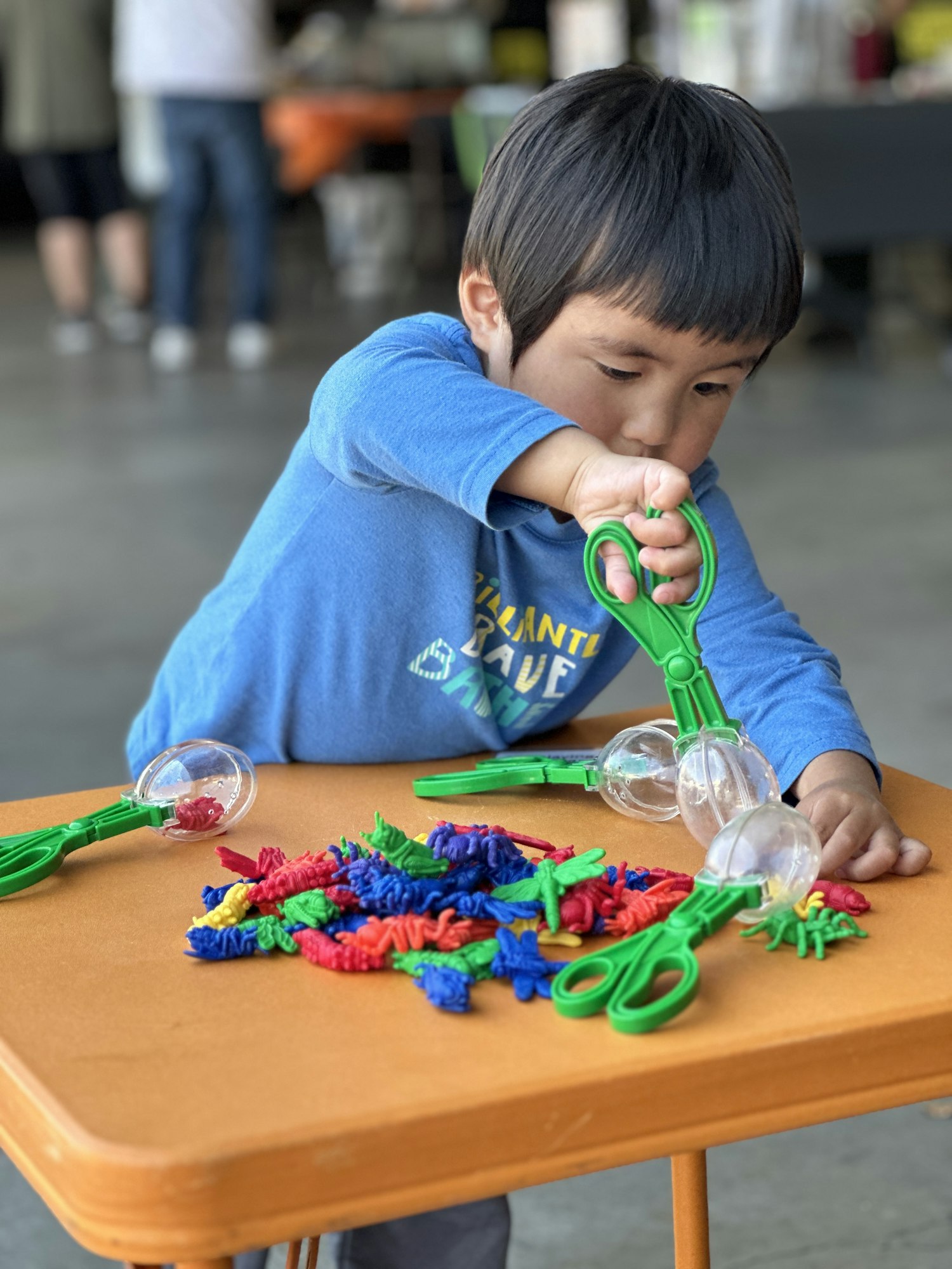 Photograph of a child playing with toys on a little orange table.