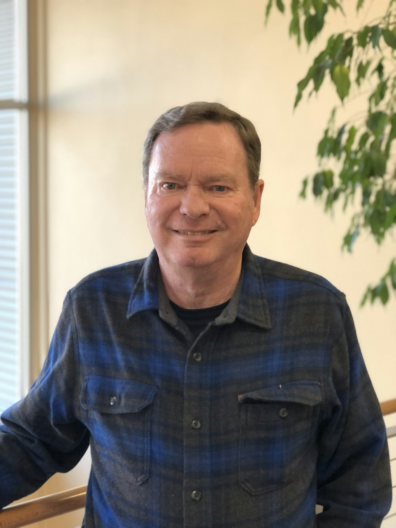 Photo of man in plaid black and blue shirt looking at the camera