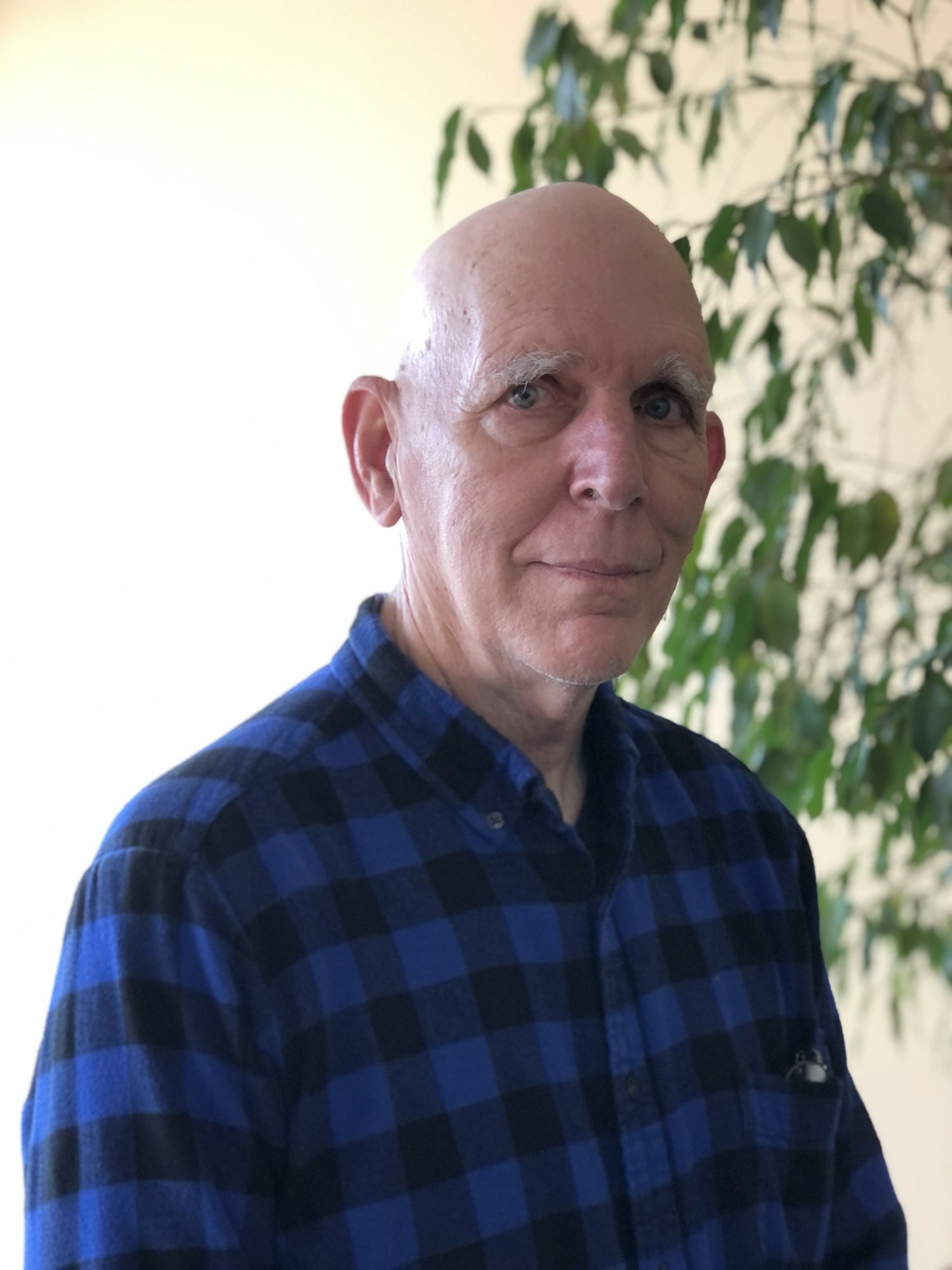 Photo of man in plaid black and blue shirt looking at the camera