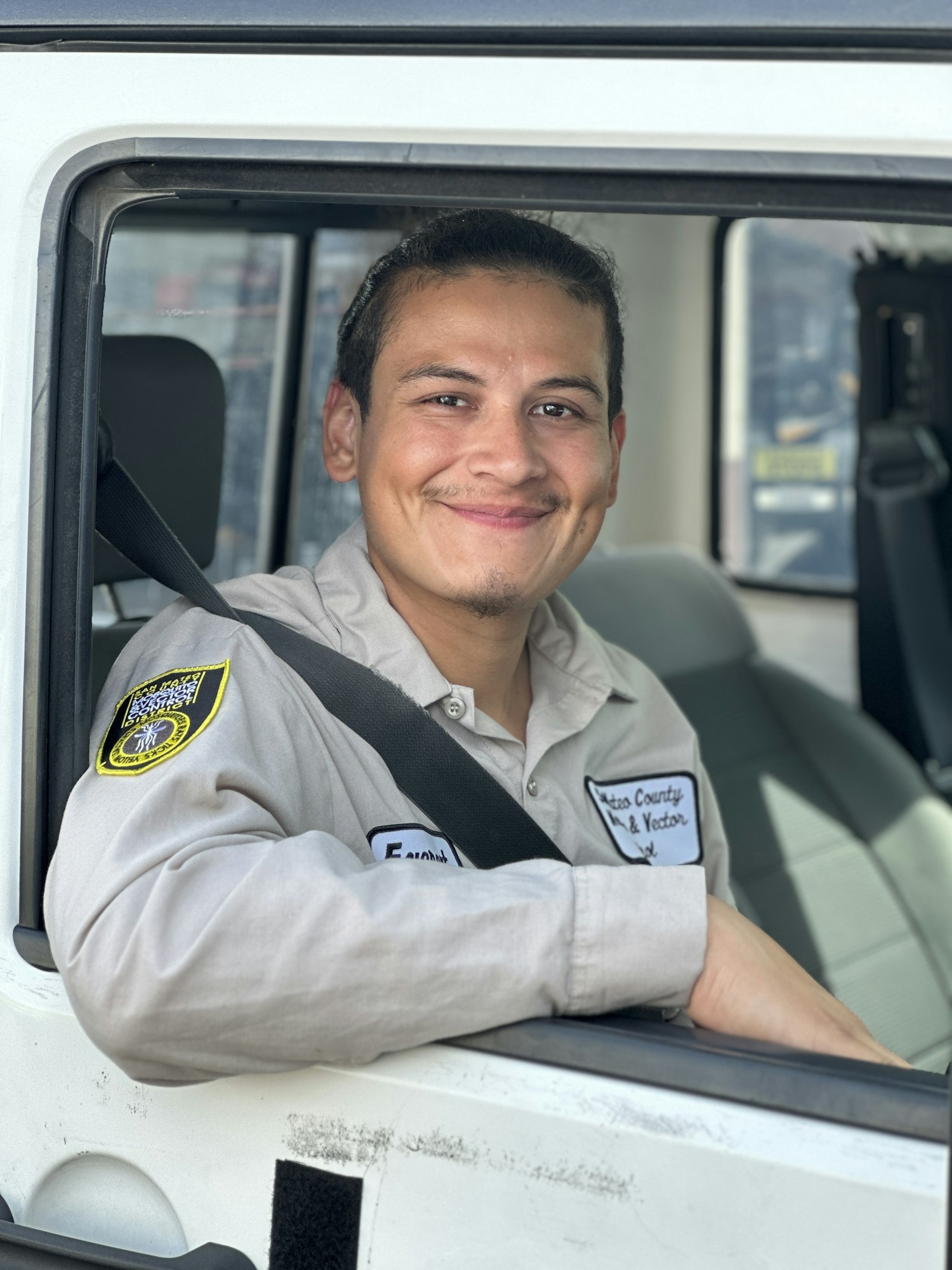 Photograph of a person looking at the camera from the seat of a vehicle, wearing a uniform