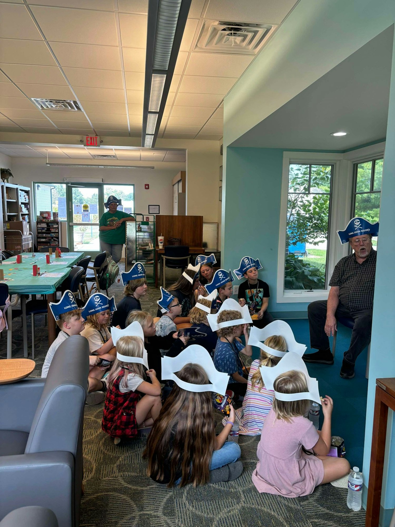 A group of children wearing pirate hats, sitting indoors, likely engaged in a storytelling or educational event.