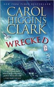 A book cover titled "WRECKED" by Carol Higgins Clark, featuring a stormy sky, a seagull, and a damaged house on stilts.