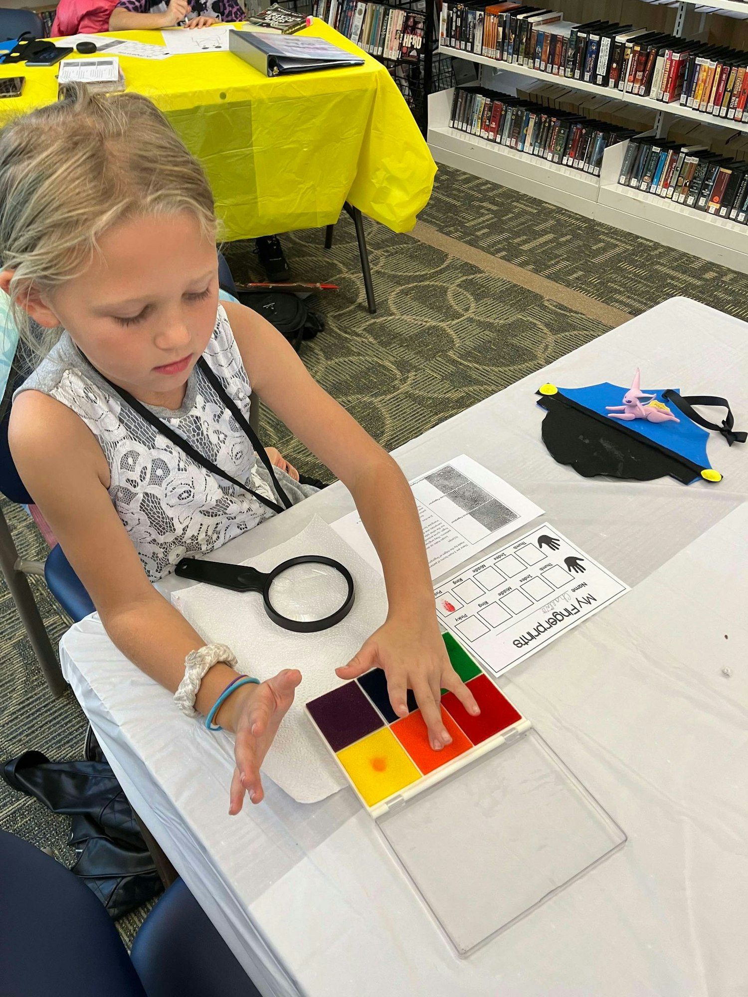 A child is engaged in an activity with colorful translucent squares and a magnifying glass on a table.