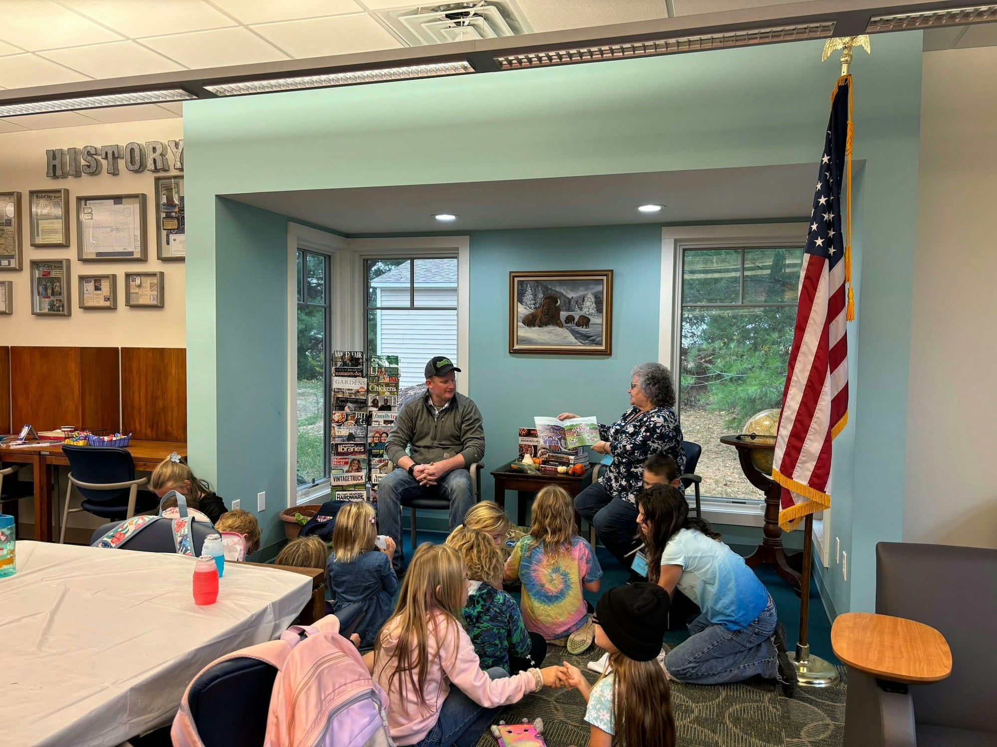 A storytelling session with children listening attentively to an adult reading a book, in a room decorated with historical items.